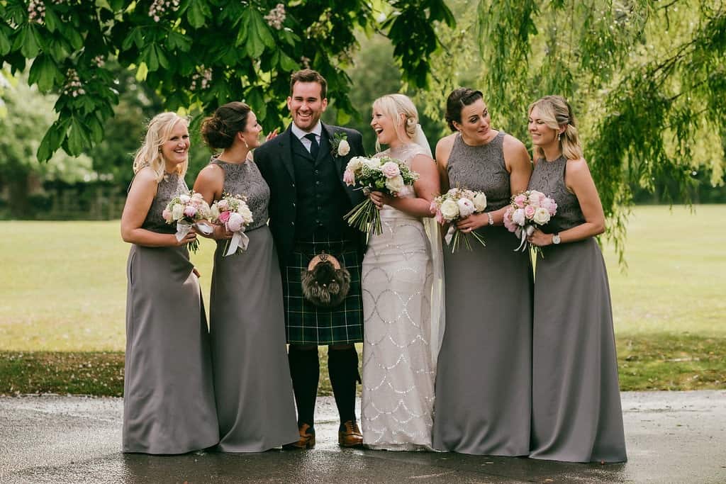 to-be couple laughing with bridesmaids in greenery
