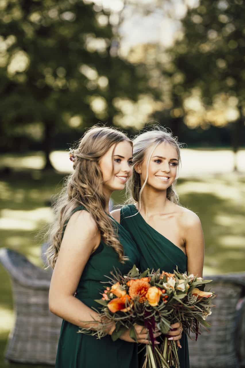 bridesmaids holding flowers in field taking picture
